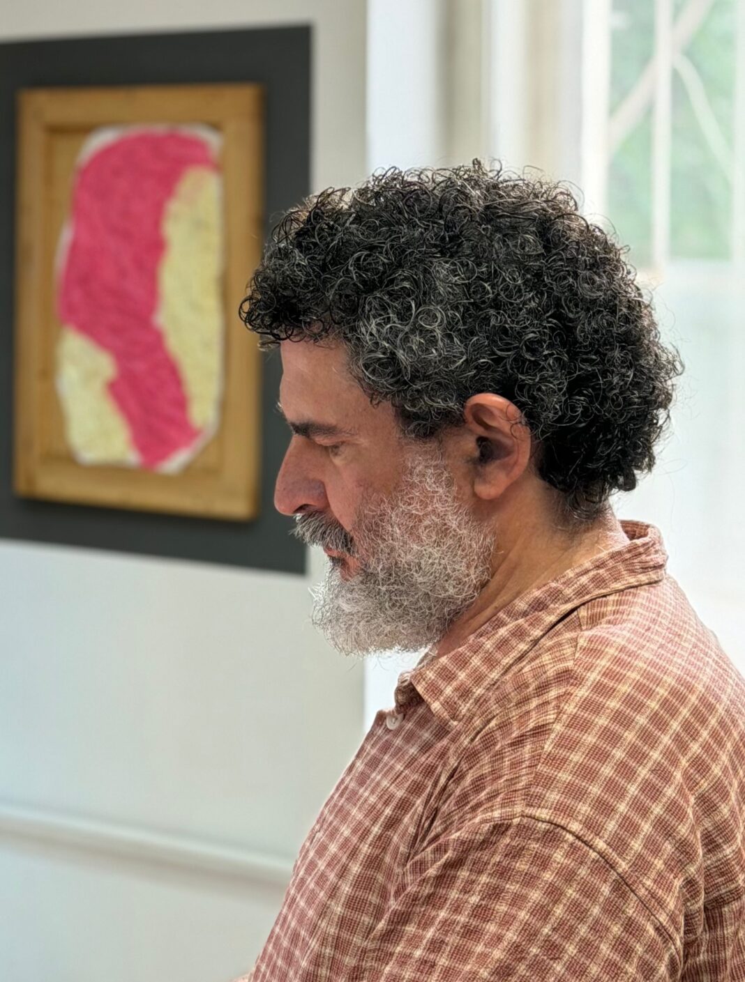 Nicolae Comănescu căzut pe gânduri în chiar mijlocul expoziției sale, fără să știe că se găsește nu departe de un Auto-Portret al său în viziunea fotografului. Foto: Peter Sragher
